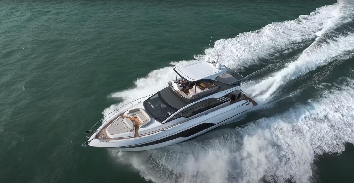 Luxury motor yacht speeding across the turquoise water, leaving a wake behind, showcasing its sleek design and spacious deck.